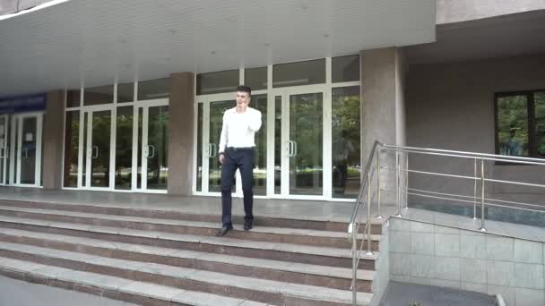 Business Kaukasische mannelijke praten op telefoon lopen weg deur op kantoorgebouw trappen — Stockvideo