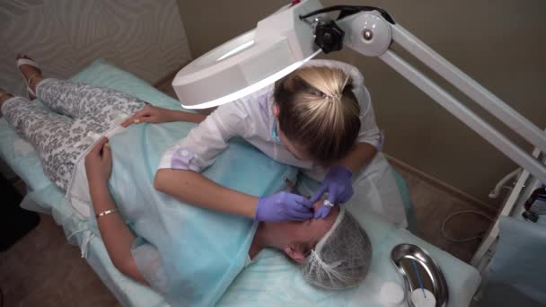 Красавчик делает процедуру пациент тянет брови Mikrobleyding клиента Постоянная татуировка, Реконструкция бровей, микро пигментация — стоковое видео