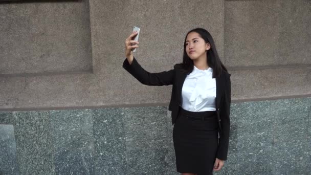 Jovem mulher de negócios bonita fêmea menina retrato segurar uso telefone tomar fazer selfie moderna no fundo escritório edifício ao ar livre — Vídeo de Stock