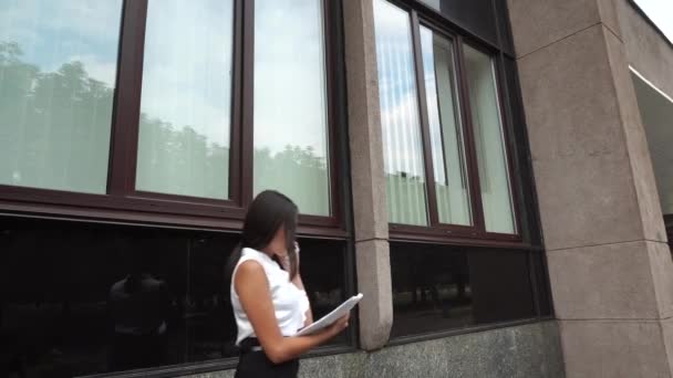 Junge schöne Geschäftsfrau weiblich Mädchen Porträt Gespräch am Telefon halten Dokumente zu Fuß auf Hintergrund Bürogebäude im Freien — Stockvideo