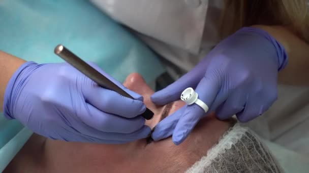 L'esthéticienne des mains rend la procédure patiente dessine les sourcils Tatouage permanent du client Mikrobleyding, Reconstruction des sourcils, Micro pigmentation — Video