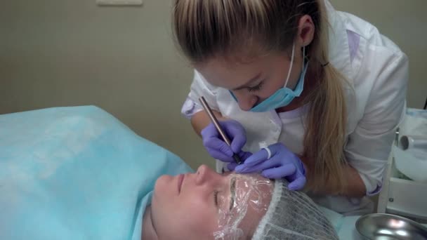 Kosmetikerin macht Eingriff Patient zieht Augenbrauen mikrobleyding Client permanente Tätowierung, Augenbrauen Rekonstruktion, Mikropigmentierung — Stockvideo