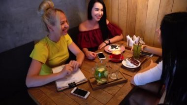 Üç güzel kadın gülümseme Cafe içinde konuşma, sırları, söyle yemek, kahve iç.