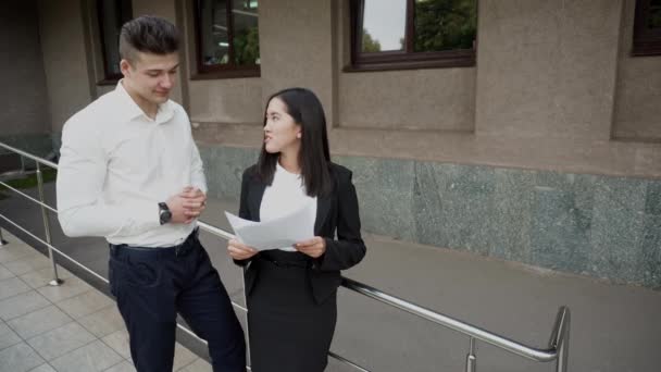 Giovane bella asiatico affari donna femmina e caucasico maschio sguardo a documenti talk su ufficio costruzione sfondo — Video Stock