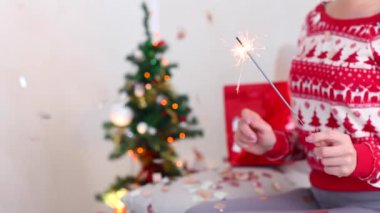 Young Girl Uses Hand Hold Sparklers, Bengal Fire Christmas Tree on Bokeh Xmas Eve Lights New Year Tree Confetti