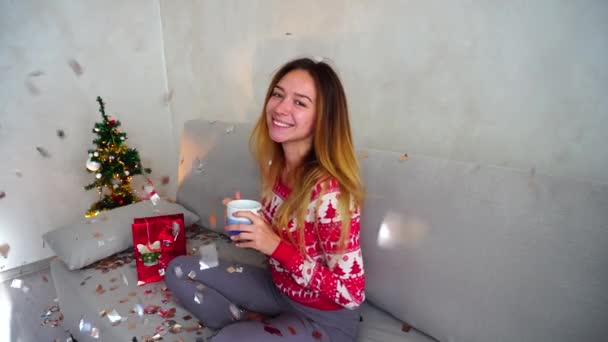 Jeune fille portrait sourire à la caméra, regarder boire du thé café arbre de Noël Bokeh Noël Veille Lumières Nouvel An Confetti — Video