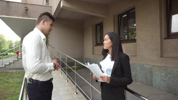 Mladá žena žena krásné asijské obchodní a kavkazské mužský pohled na dokumenty mluvit na schodech kancelářská budova — Stock video