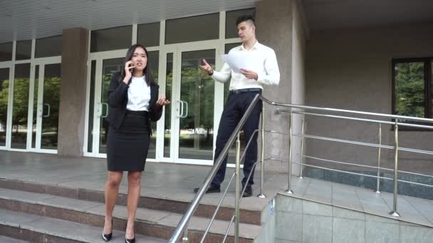 Young Beautiful Asian Business Woman Female and Caucasian Male Look at Documents, Talk on Phone Office Building Stairs — ストック動画