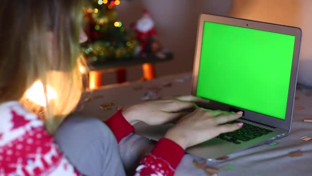 La mano de la mujer de la pantalla verde presiona el toque en el teclado del ordenador portátil, enciende el fondo de Bokeh del árbol de Navidad en la noche . — Vídeo de stock