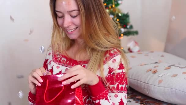 Joven chica utiliza mano agarre presente, regalo estrella en Bokeh Navidad luces árbol de año nuevo Confetti Navidad — Vídeos de Stock