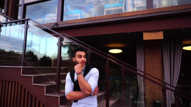 Portrait of Young Thinking Arab Businessman Looking to Side at Camera and Smiling on Background European Business Restaurant Stairs — ストック動画