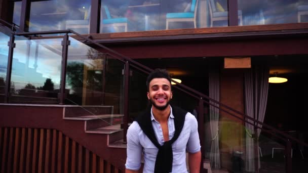Portré, fiatal Arab üzletember keresi a kamera, és mosolyogva a háttér európai üzleti étterem lépcsők — Stock videók