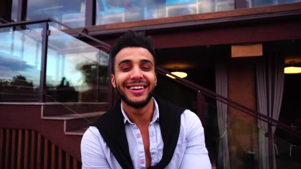 Портрет Арабські бізнесмен чекати, дивлячись на стороні і на камеру і посміхається на тлі Європейської бізнес ресторан сходи — стокове відео