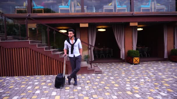 Young Arabian Male Man Entrepreneur Standing Waiting With Travel Bag in Hand, Smiling at Camera on Background of Restaurant With Hand in Pocket. — Stock video