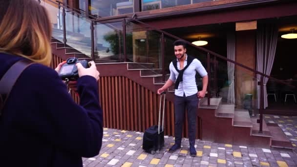 Junger arabischer Geschäftsmann posiert für Foto mit Koffer in der Hand auf der Treppe eines Restaurants. — Stockvideo