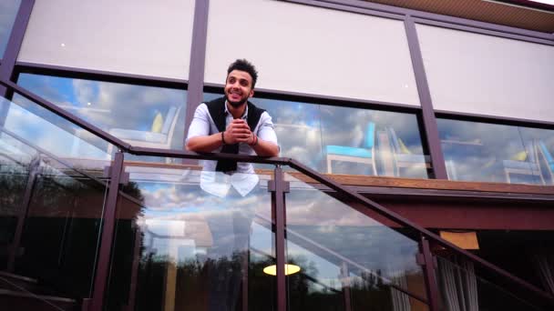 Stately árabe masculino homem sorrindo e em pé escadas e olha para fora de escadas de restaurante e olha em volta . — Vídeo de Stock