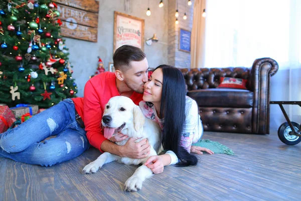 Sweet couple kissing, posing and smiling at camera, beside dog i — Stock Photo, Image