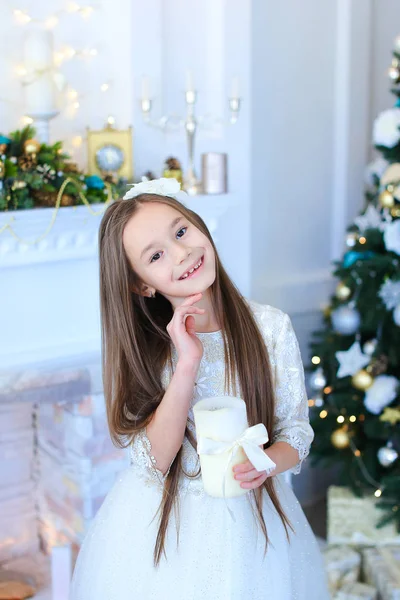Mädchen lächelt und posiert vor der Kamera, hält Kerze auf dem Hintergrund — Stockfoto