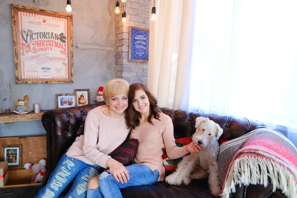 Hija con la madre sentada juntos en el sofá al lado del perro, smil —  Fotos de Stock