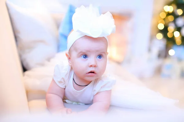 Bébé fille couché sur le canapé et regardant de côté dans le studio blanc . — Photo