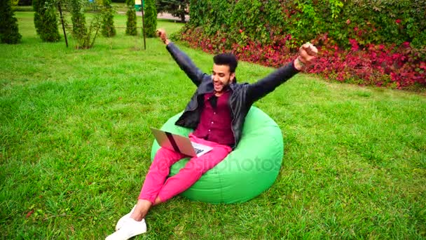 Successful Arabic Entrepreneur Sits With Laptop in Chair, Stares at Laptop Screen, Raises Hands, Making Hand Gesture "yes!" in Garden Outdoors. — Stock Video