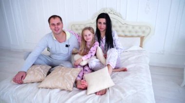 Gülümseyen ve kamera yatak ev bakarak pijama mutlu bir aile portresi