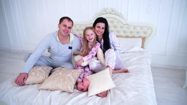 Retrato familia feliz en pijama sonriendo y mirando la cámara en la cama — Vídeos de Stock