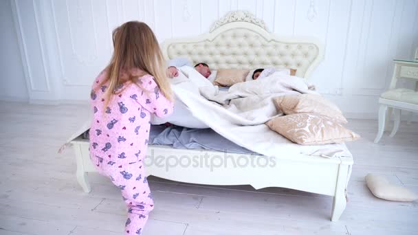 Kız bebek anne yatakta uyanır, battaniyenin altında tırman. — Stok video