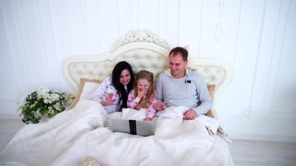 Filha pequena e pais falam chamada de vídeo na cama branca . — Vídeo de Stock
