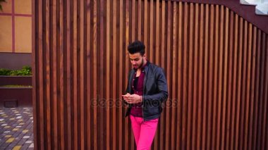 Sevimli genç Arap adam telefon alır sevinir ne görür, gülümsüyor ve arka plan açık havada merdivenin üzerinde duruyor.