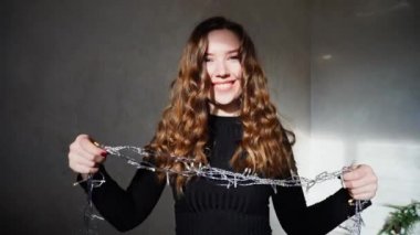 Noel ışıkları ile oynama ve gülümseyen, Bright Kış Güneşi vuruşta kız portresi