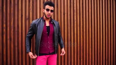 Yakışıklı genç Arapça adam kamera için poz ve ceket veya saç, düzeltiyor gülümsüyor ve merdiven arka plan açık havada etrafına bakıyor.