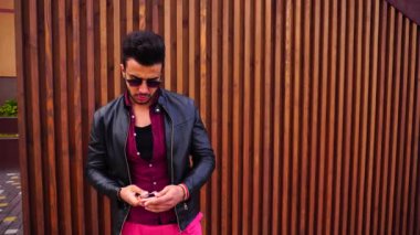 Yakışıklı genç Arapça adam kamera için poz ve ceket veya saç, düzeltiyor gülümsüyor ve merdiven arka plan açık havada etrafına bakıyor.