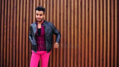 Yakışıklı genç Arapça adam kamera için poz ve ceket veya saç, düzeltiyor gülümsüyor ve merdiven arka plan açık havada etrafına bakıyor.