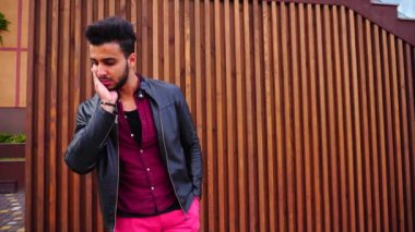 Yakışıklı genç Arapça adam kamera için poz ve ceket veya saç, düzeltiyor gülümsüyor ve merdiven arka plan açık havada etrafına bakıyor.