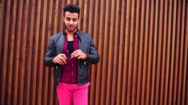 Yakışıklı genç Arapça adam kamera için poz ve ceket veya saç, düzeltiyor gülümsüyor ve merdiven arka plan açık havada etrafına bakıyor.