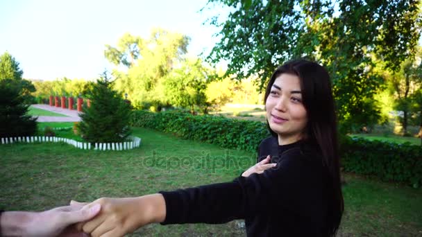 Affascinante giovane donna tiene le mani e parla con giovane uomo, sorrisi e risate, guarda la fotocamera e in posa. Ragazza Situato a Green Park all'aperto . — Video Stock