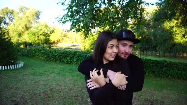 Linda pareja hablando y abrazándose y posando en la cámara, de pie en Green Park al aire libre . — Vídeos de Stock