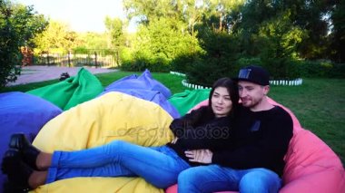 Yeni evli Sit ve koltuklar, konuşmasında gülümseme birbirlerine ve açık havada Park sarılma.