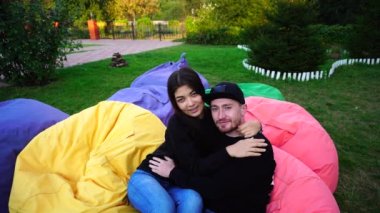 Yeni evli koltuklar içinde poz ve her diğer, okşayarak ve büyük açık hava parkta otururken sarılma.