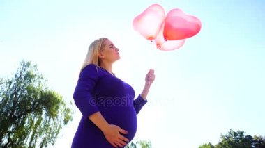 Muhteşem gelecek Mother Holding ve güneş ışığı, arka plan üzerinde elinde döner Ballons teşkil etmektedir ve tatlı bir şekilde, okşayarak Tummy gülümsüyor.