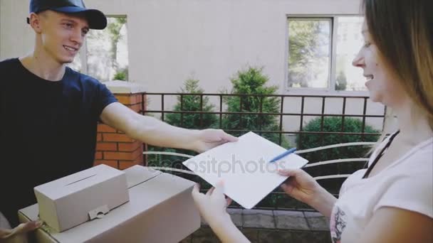Carteiro dando caneta e documentos para menina, mulher coloca assinatura e toma ordem e folhas de correio . — Vídeo de Stock