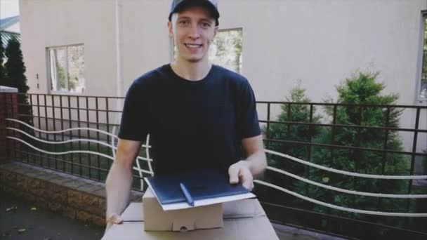 Bezorger gebracht-ordeklanten, Guy geeft papier en Pen te ondertekenen voor levering op achtergrond van huis buitenshuis overdag. — Stockvideo