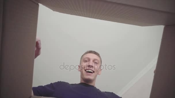 L'uomo apre la scatola sorridendo allungando le braccia all'interno dell'involucro e sorridendo . — Video Stock