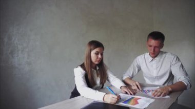 Erkek ve kadın iş çizelgeleri, kağıt ve belgeler Office masada oturan tartışıyor.