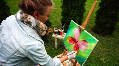 Güzel sanatçı fırçalar tutar ve resim arka plan detaylarını sonuçlandırılması, Park arka plan ağaç ve sanat ile tezgah üzerinde tribünlerde araçları açık havada.