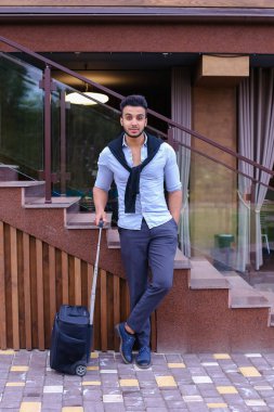 Çekici genç Arap adam elinde bavulla ayakta ve p