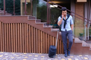 Çekici genç Arap adam elinde bavulla ayakta ve p