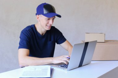 Postane bilgisayarda yazarak masada oturan kurye.
