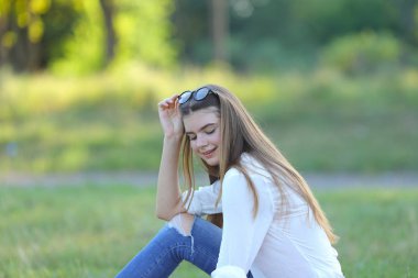 gülümseyen ve diz üstü çalışma parkta oturan genç kız.